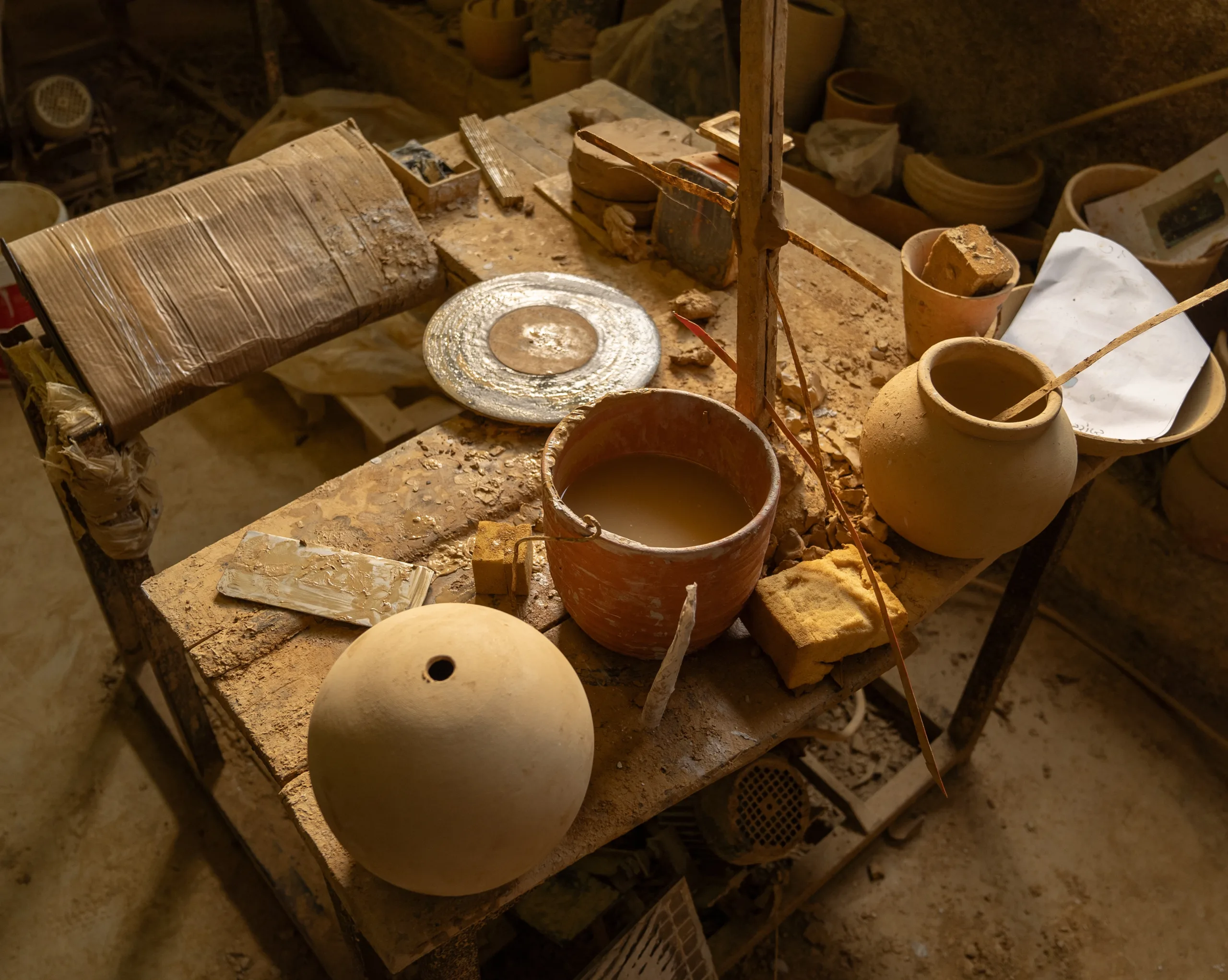 Atelier de poterie traditionnelle – Fuko Plan de travail d’un artisan potier avec des pièces en cours de création