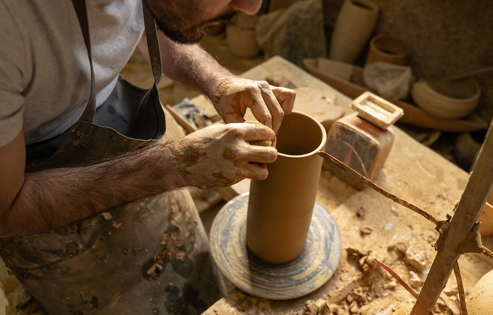 Savoir-faire artisanal en action – Fuko Mains d’un artisan façonnant une pièce en argile sur un tour de potier